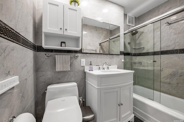 bathroom featuring toilet, visible vents, bath / shower combo with glass door, and vanity