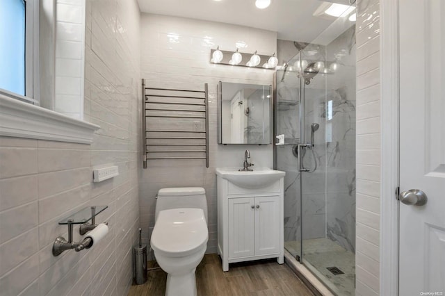 full bath with toilet, wood finished floors, vanity, radiator, and a stall shower