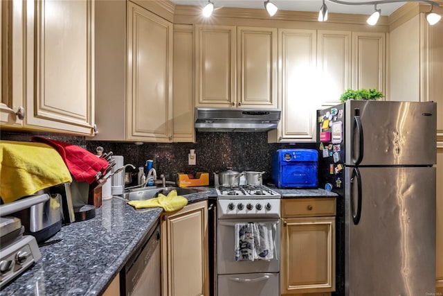 kitchen with sink, tasteful backsplash, dark stone countertops, track lighting, and appliances with stainless steel finishes