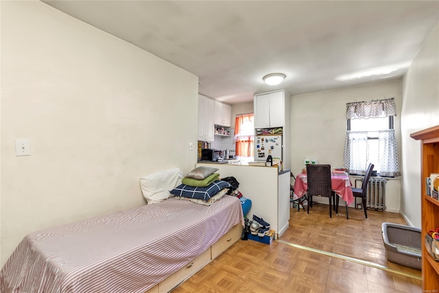 bedroom featuring light parquet flooring and white refrigerator