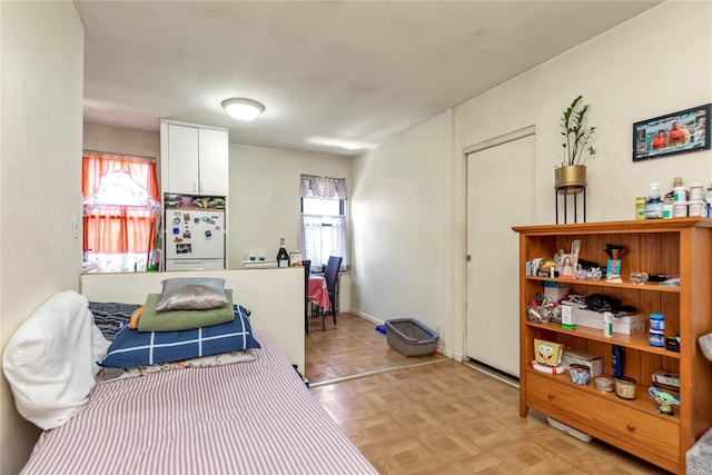 bedroom featuring light parquet flooring, white refrigerator, a closet, and multiple windows