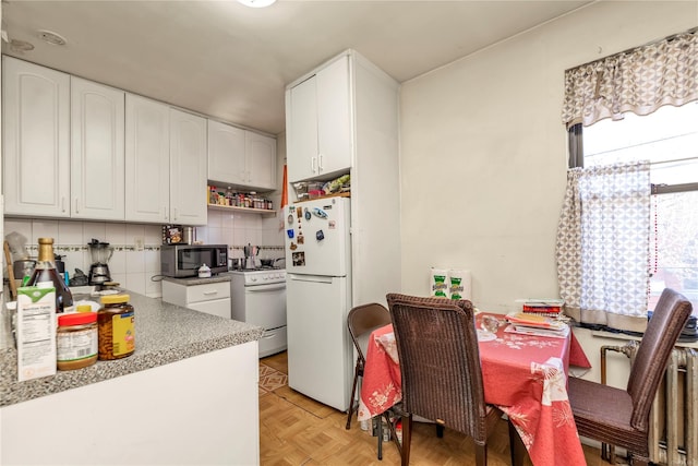 kitchen with white cabinets, decorative backsplash, white appliances, and light parquet floors