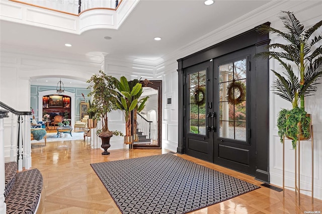 foyer entrance featuring french doors, light parquet flooring, and ornamental molding