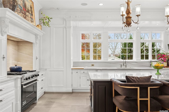 kitchen featuring white cabinetry, high end stainless steel range, plenty of natural light, and sink