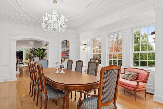 dining room featuring light wood-type flooring, crown molding, and a notable chandelier