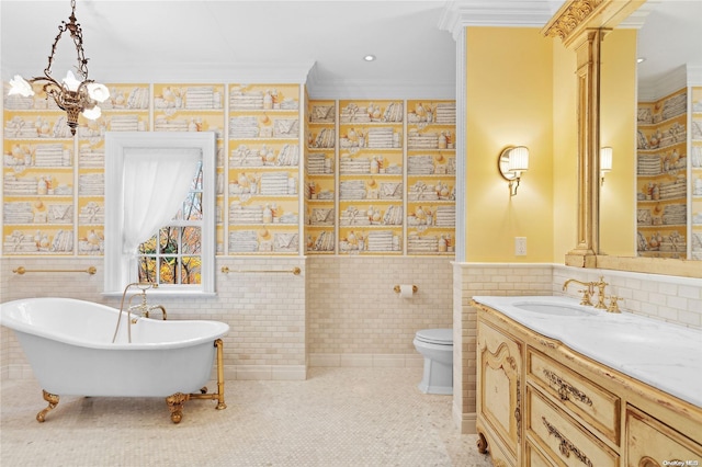 bathroom with a washtub, toilet, vanity, tile walls, and ornamental molding