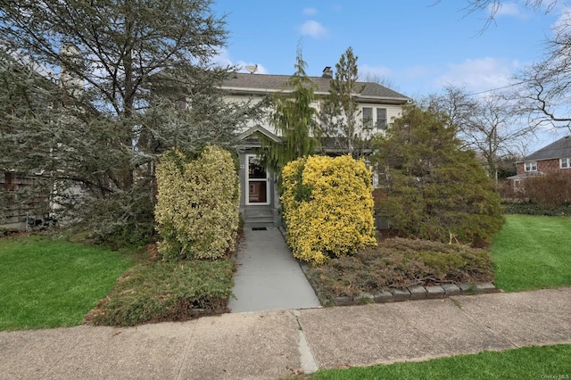 view of property hidden behind natural elements featuring a front yard