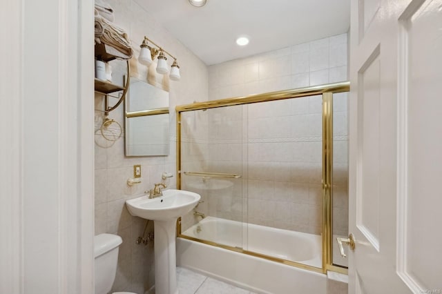 bathroom featuring tile patterned floors, toilet, enclosed tub / shower combo, and tile walls