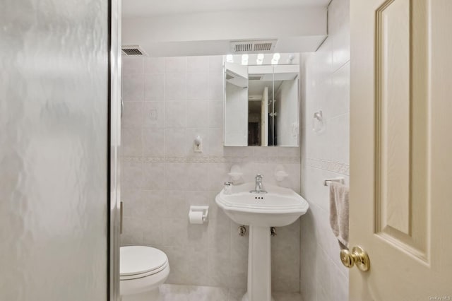 bathroom with tile walls and toilet