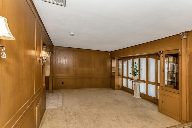 spare room featuring light carpet and wood walls