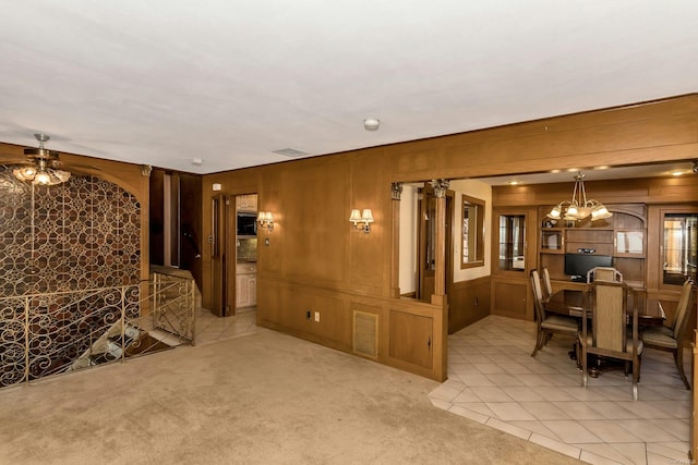 interior space with light colored carpet, an inviting chandelier, and wood walls