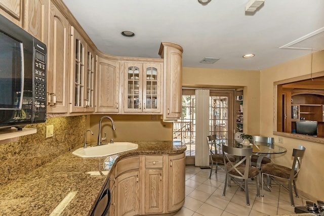 kitchen with sink, light tile patterned floors, decorative backsplash, dark stone counters, and light brown cabinets