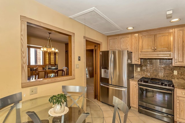 kitchen with appliances with stainless steel finishes, tasteful backsplash, light stone countertops, decorative light fixtures, and a chandelier