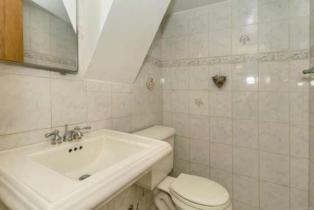 bathroom featuring tasteful backsplash, toilet, sink, and tile walls