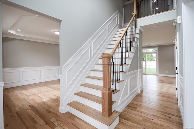 stairs with crown molding and hardwood / wood-style flooring