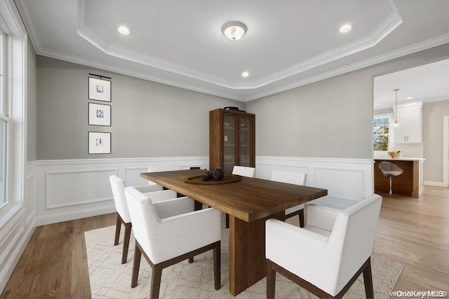 dining room featuring light hardwood / wood-style floors, a raised ceiling, and crown molding