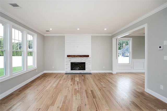 unfurnished living room featuring a large fireplace, light hardwood / wood-style flooring, and a wealth of natural light