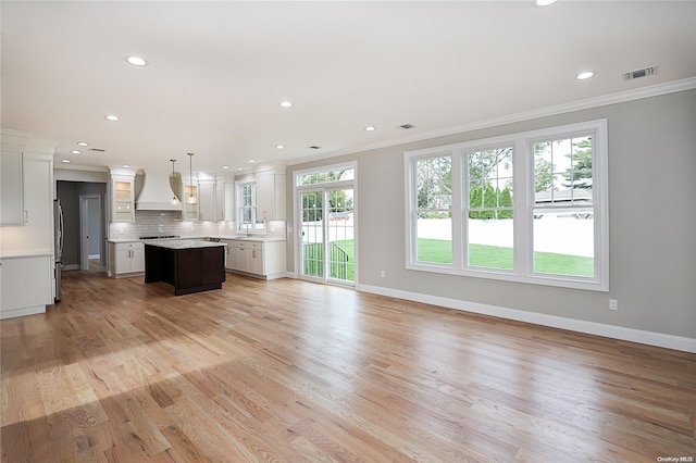 unfurnished living room with ornamental molding, sink, and light hardwood / wood-style flooring