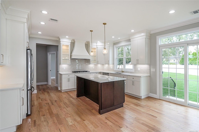 kitchen with white cabinetry, a center island, black gas stovetop, custom exhaust hood, and light wood-type flooring