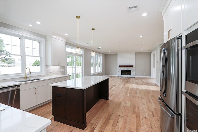 kitchen with white cabinetry, sink, light hardwood / wood-style floors, a kitchen island, and appliances with stainless steel finishes