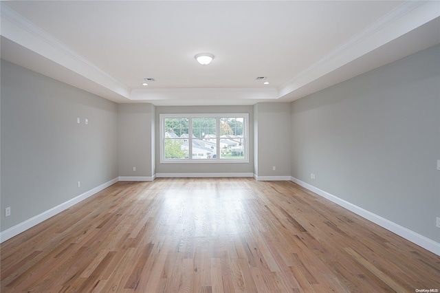 unfurnished room featuring light wood-type flooring, ornamental molding, and a tray ceiling