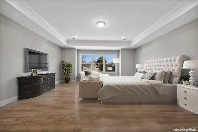 bedroom featuring a tray ceiling, hardwood / wood-style floors, and ornamental molding