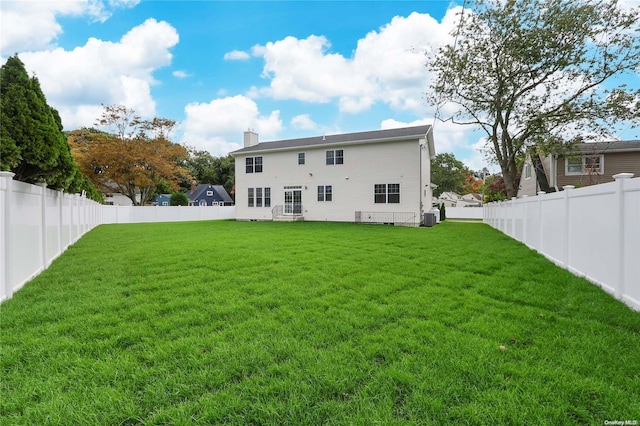 back of property featuring a yard and central AC