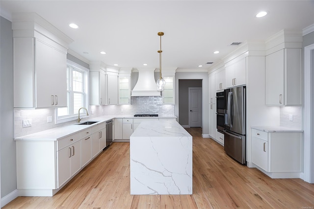 kitchen featuring white cabinets, a kitchen island, stainless steel appliances, premium range hood, and a sink