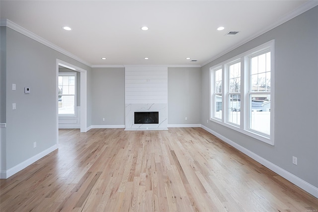 unfurnished living room featuring baseboards, light wood finished floors, a high end fireplace, and crown molding