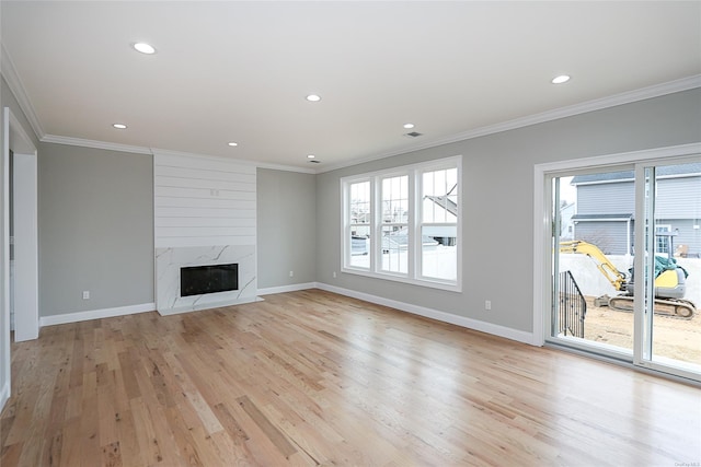 unfurnished living room featuring crown molding, light wood-style flooring, baseboards, and a premium fireplace