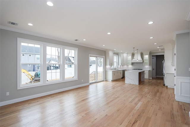 kitchen featuring premium range hood, ornamental molding, a sink, and a center island