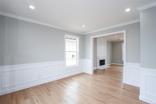 unfurnished room with light wood-style floors, a fireplace, ornamental molding, and recessed lighting