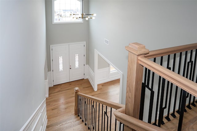 foyer with visible vents, wainscoting, a towering ceiling, wood finished floors, and a chandelier