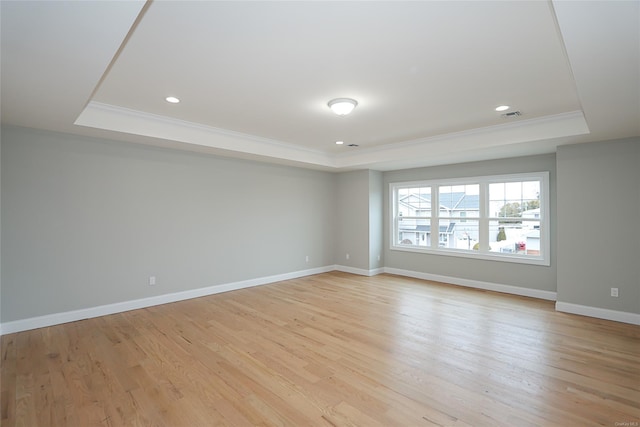 empty room with a raised ceiling, visible vents, and baseboards