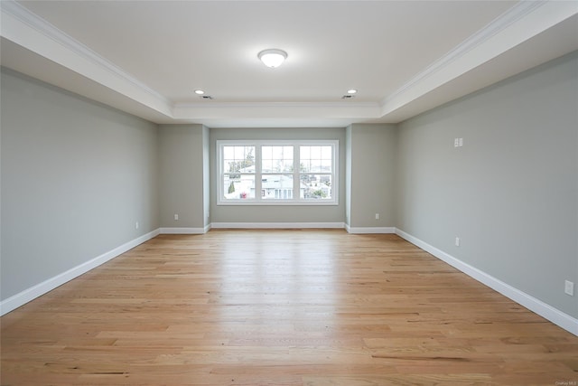 unfurnished room with a raised ceiling, crown molding, and baseboards