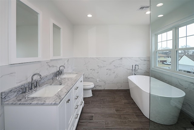 full bath featuring double vanity, a soaking tub, visible vents, and a sink