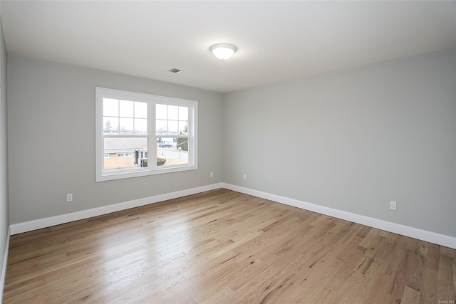 unfurnished room with wood finished floors, visible vents, and baseboards