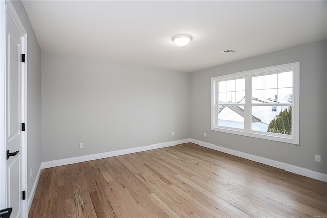 unfurnished room with light wood-style flooring, visible vents, and baseboards