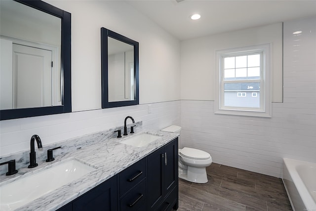 full bathroom with a tub to relax in, a sink, toilet, and double vanity