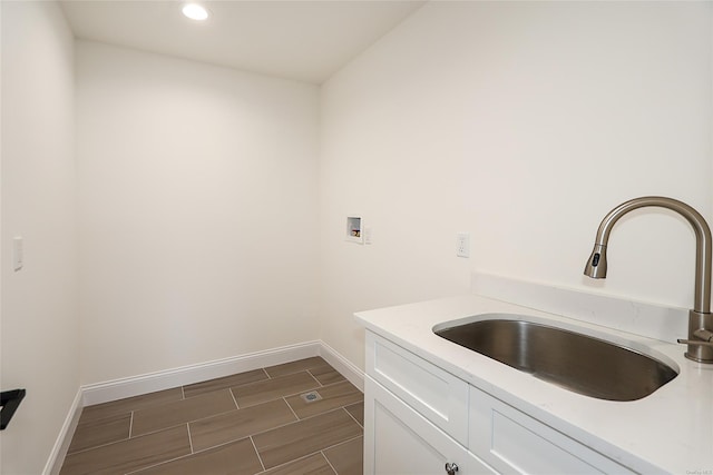 laundry area with washer hookup, cabinet space, wood tiled floor, a sink, and baseboards