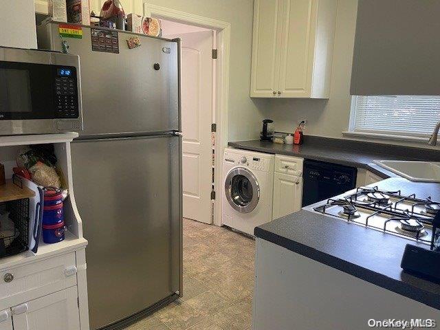 kitchen with appliances with stainless steel finishes, washer / clothes dryer, white cabinetry, and sink