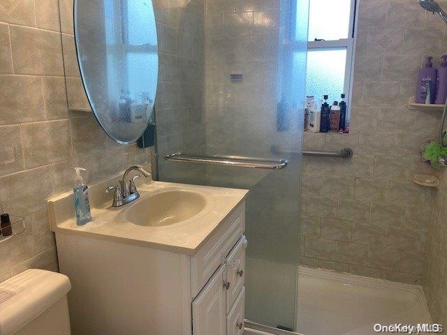 bathroom with vanity, toilet, and tiled shower