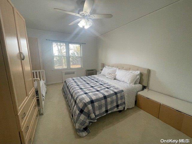 carpeted bedroom with ceiling fan and radiator