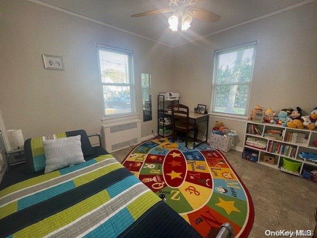 bedroom featuring ceiling fan, radiator heating unit, and ornamental molding