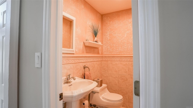 bathroom with toilet, tile walls, and sink