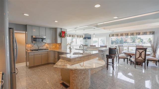 kitchen with gray cabinetry, sink, stainless steel appliances, kitchen peninsula, and decorative light fixtures