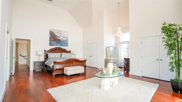 bedroom featuring dark hardwood / wood-style flooring, high vaulted ceiling, and an inviting chandelier