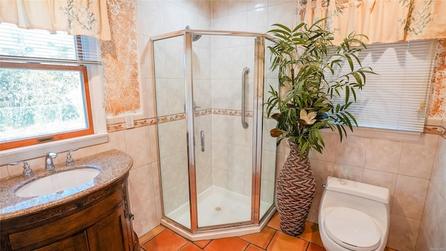 bathroom with an enclosed shower, vanity, tile walls, tile patterned flooring, and toilet