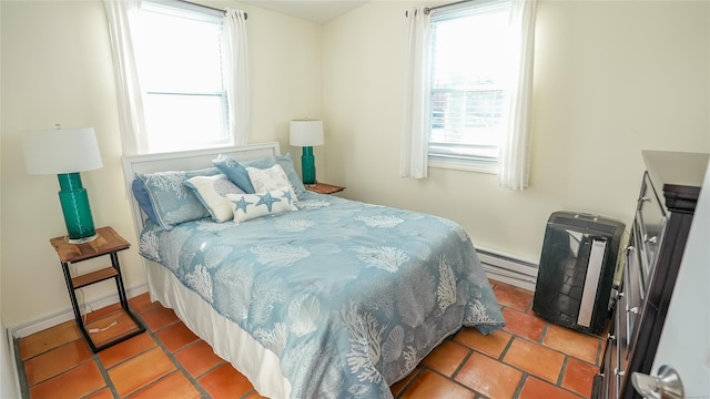 bedroom featuring tile patterned floors, baseboard heating, and multiple windows