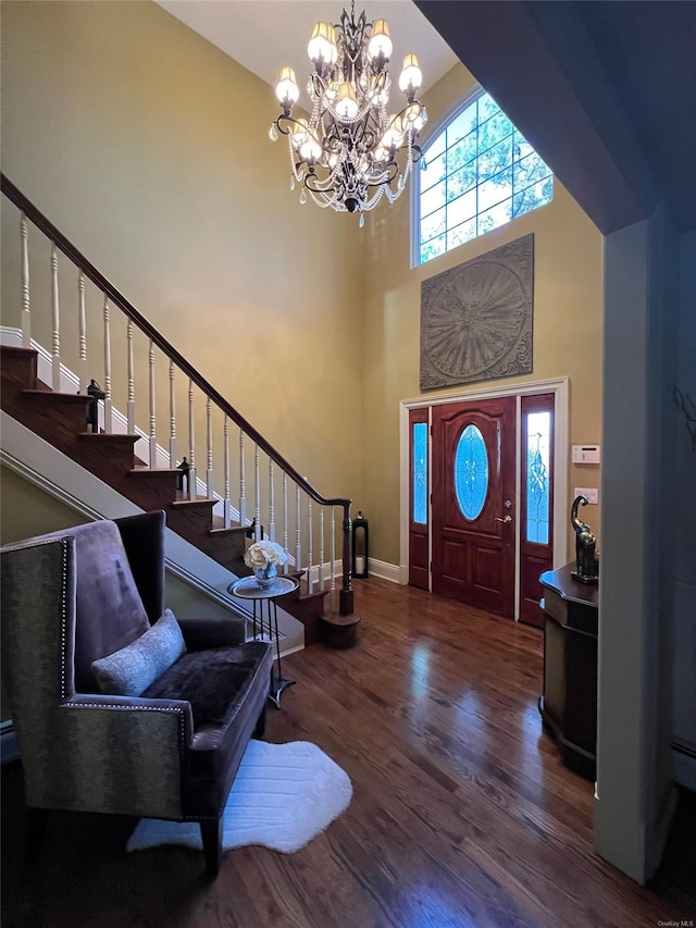 foyer with dark hardwood / wood-style flooring, a towering ceiling, and a notable chandelier